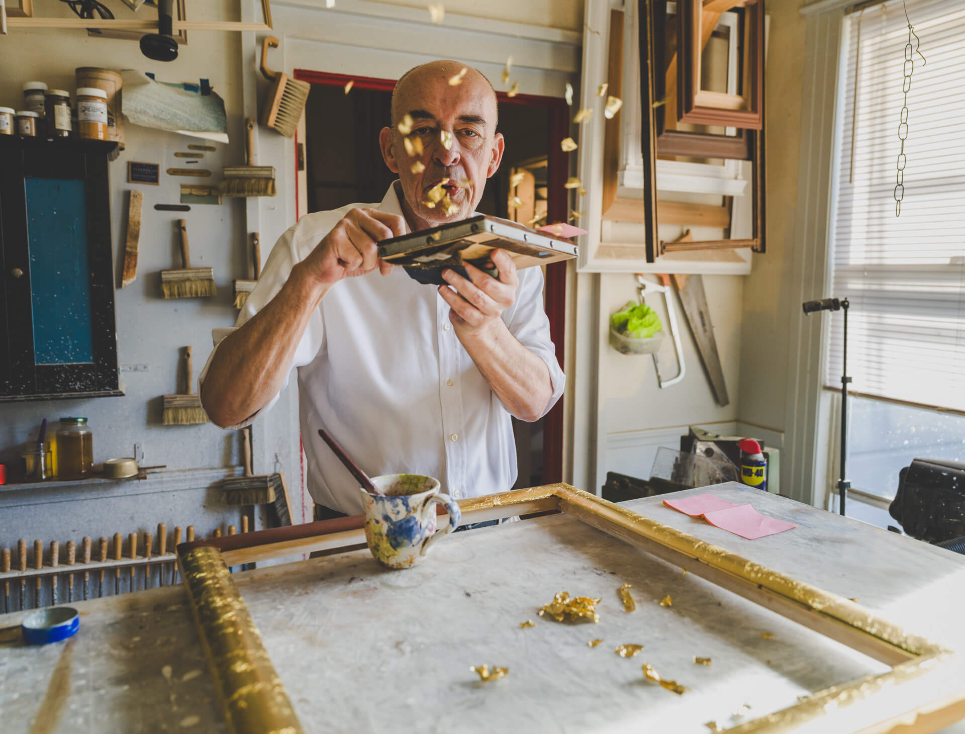 Artisan Peter Werkhoven working at a table inside the Aedicule framing and gilding studio in San Francisco