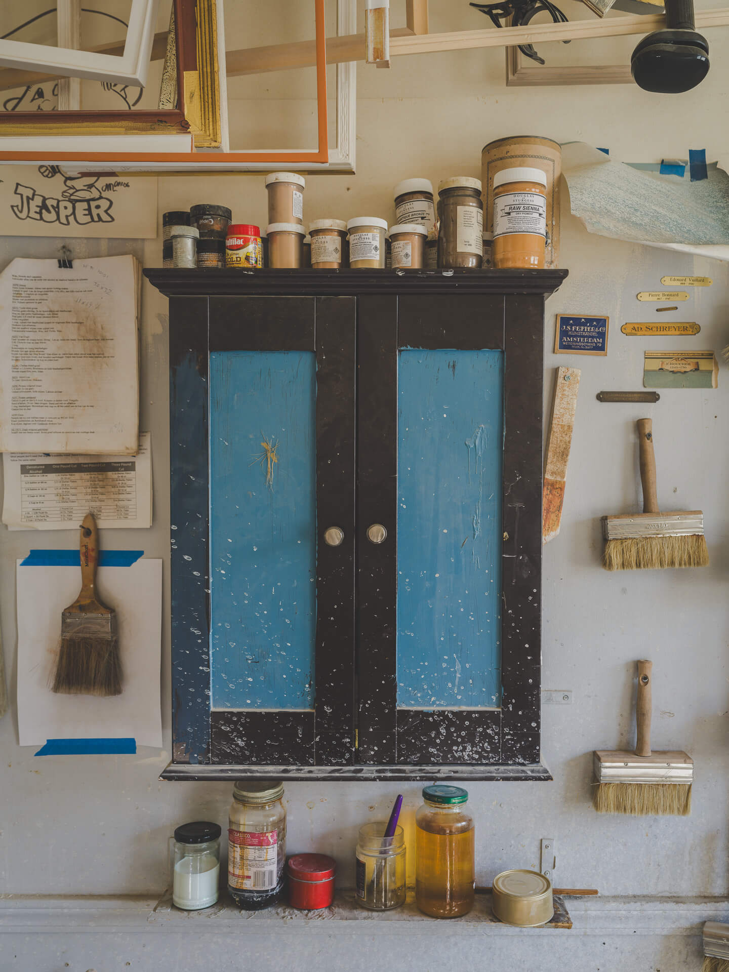 Paintbrushes, pigments and a distressed blue cabinet inside the Aedicule workshop.