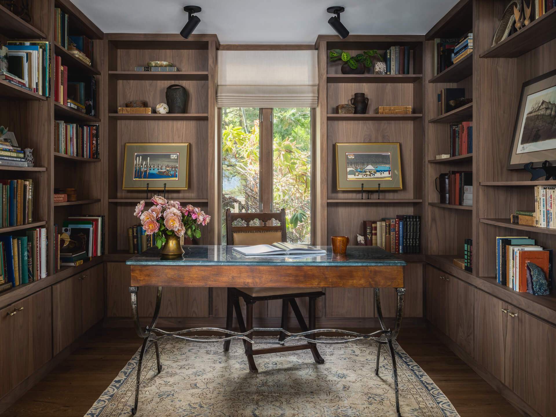 Wood-paneled home office and library with built-in bookshelves, vintage desk and garden views.