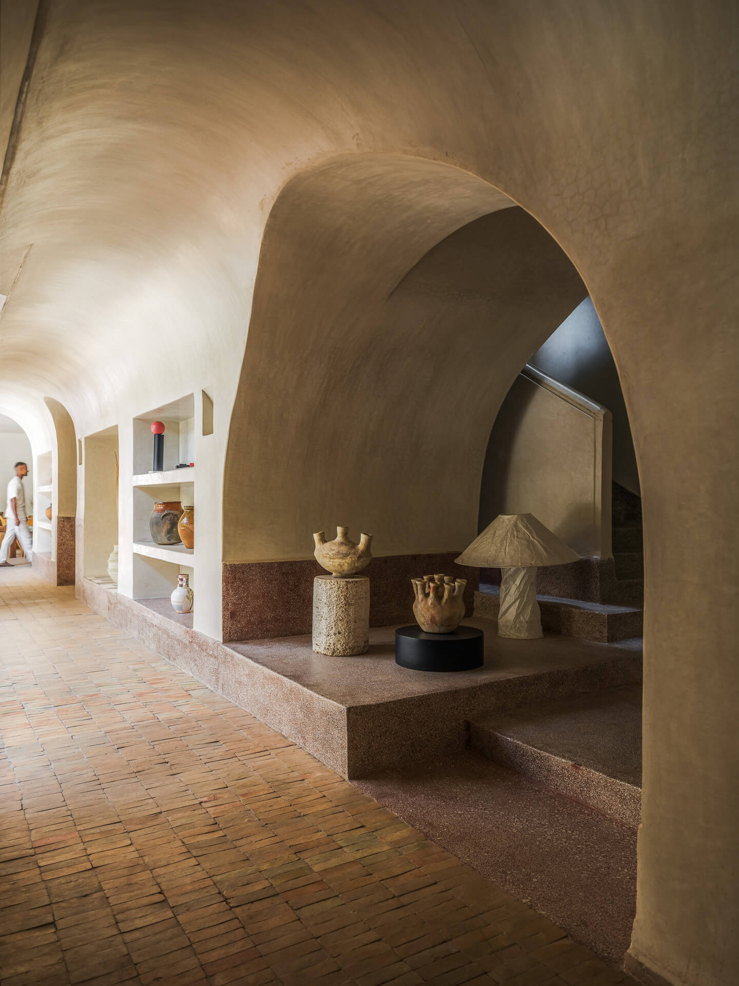 Sculptural plaster interior with curved archways, built-in seating, and warm brick flooring.