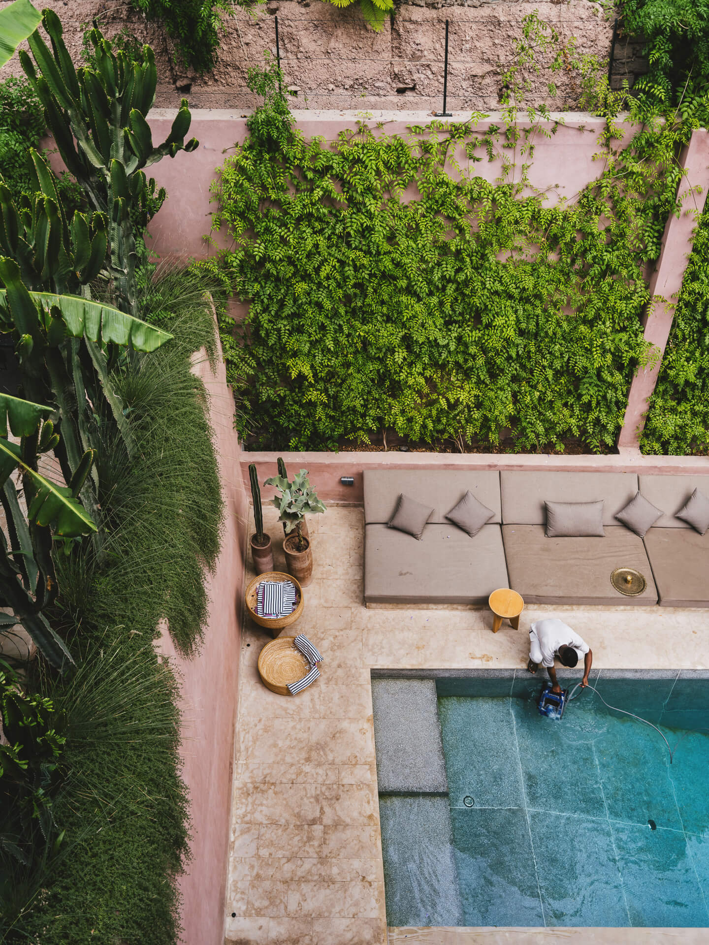 Overhead view of a courtyard with turquoise pool, outdoor seating, and lush surrounding greenery.