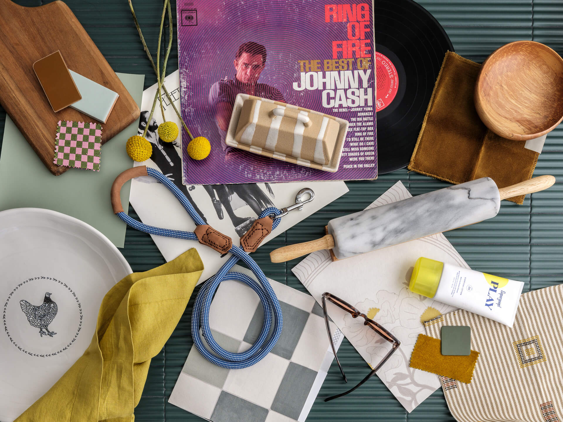 Colorful flat lay with a Johnny Cash record, fabric swatches, scissors, ceramics, flowers and small design objects