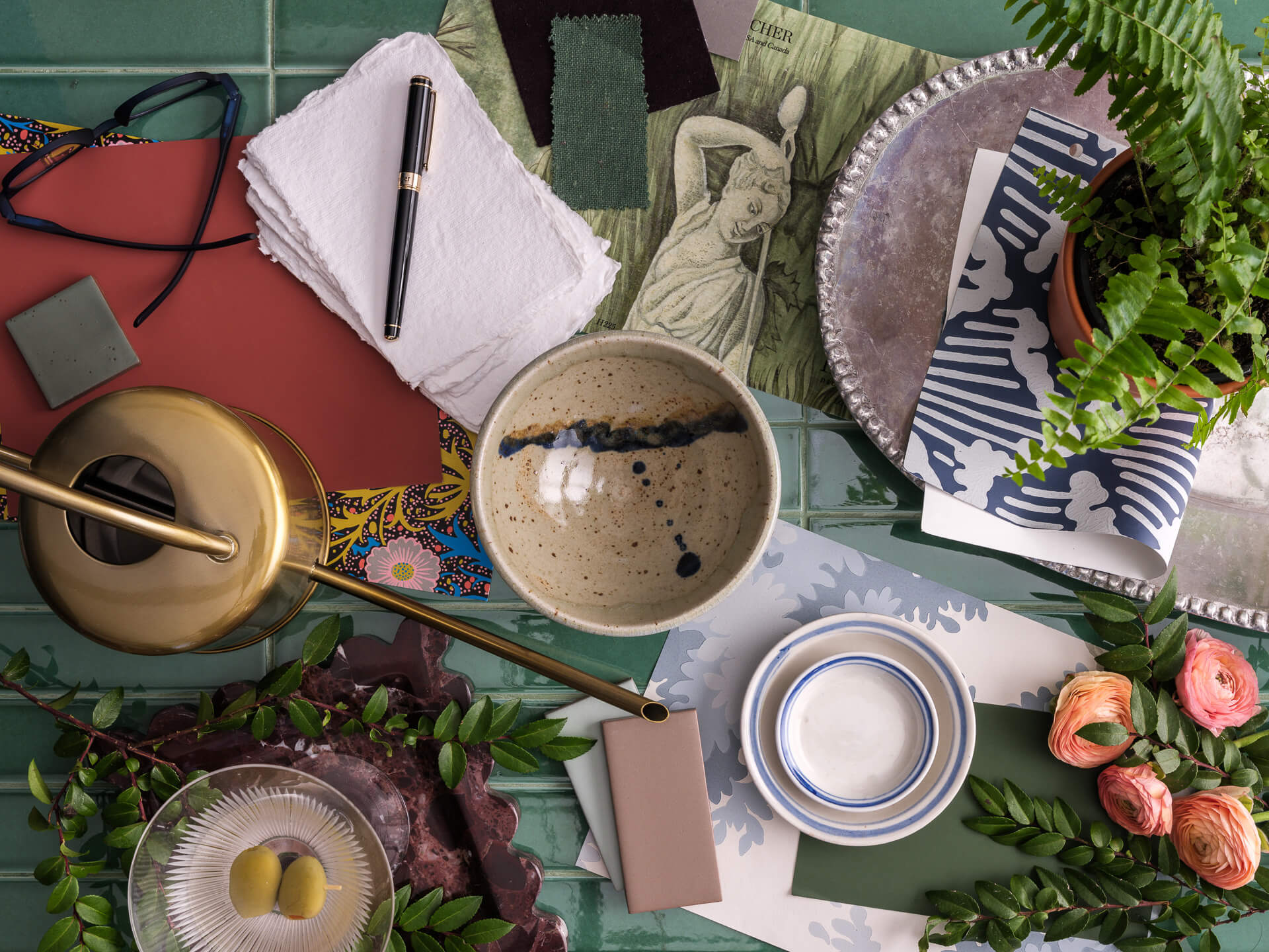 Eclectic flat lay with flowers, fabric samples, ceramics and layered decorative accessories.