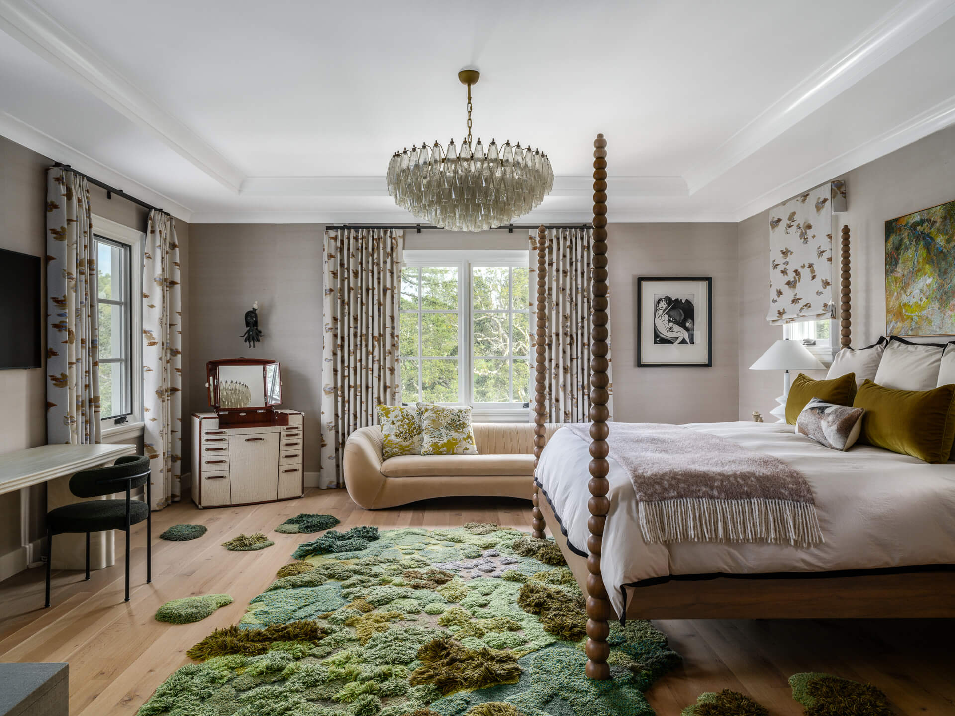 Spacious bedroom with four-poster bed, green textured rug, patterned curtains, and chandelier.