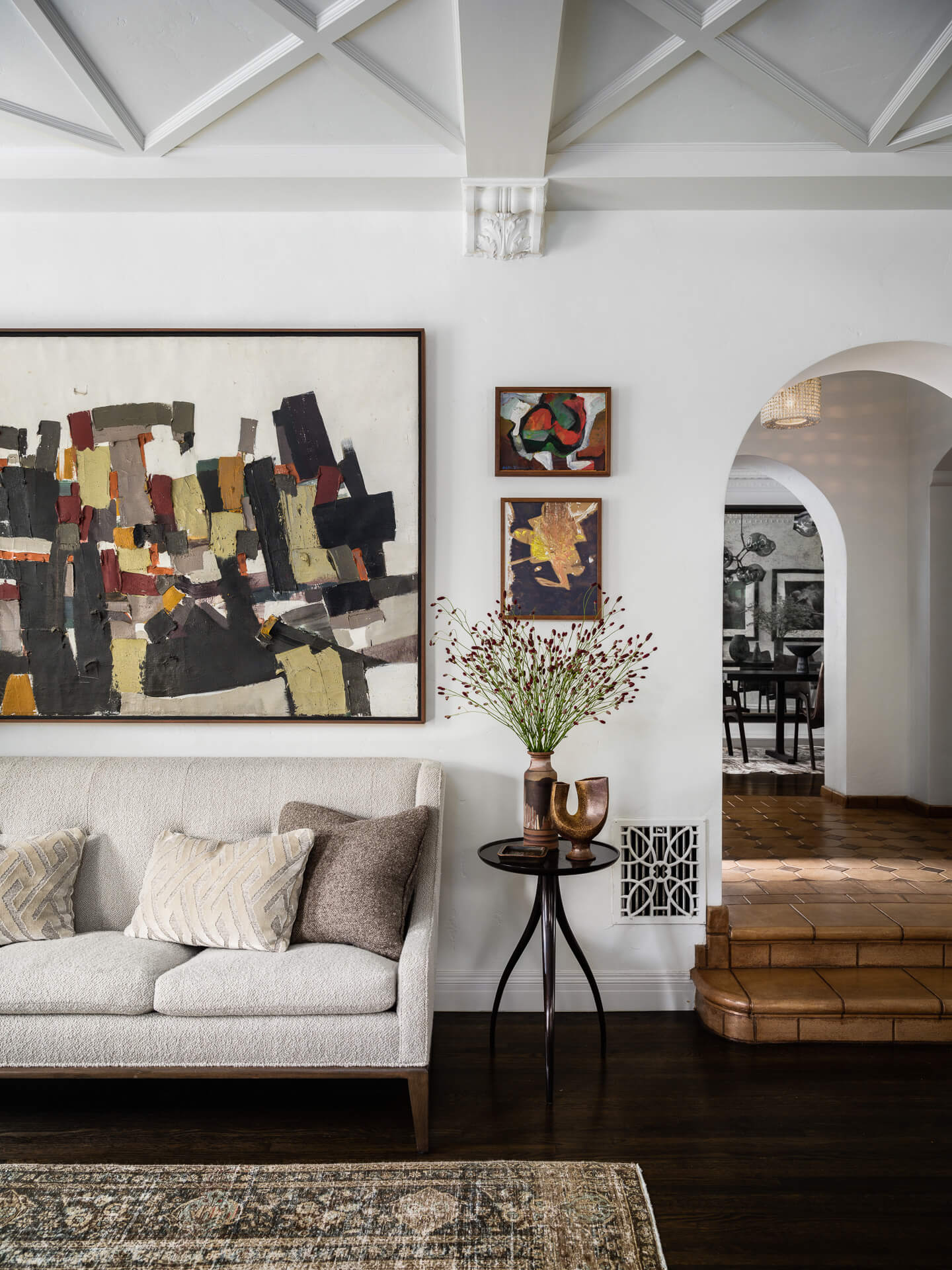 Cream sofa beneath abstract artwork beside an arched doorway and terracotta steps