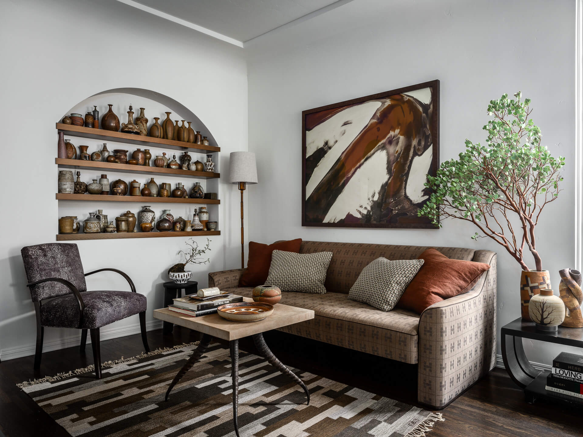 Sitting room with patterned sofa, collected ceramics, abstract artwork and sculptural greenery