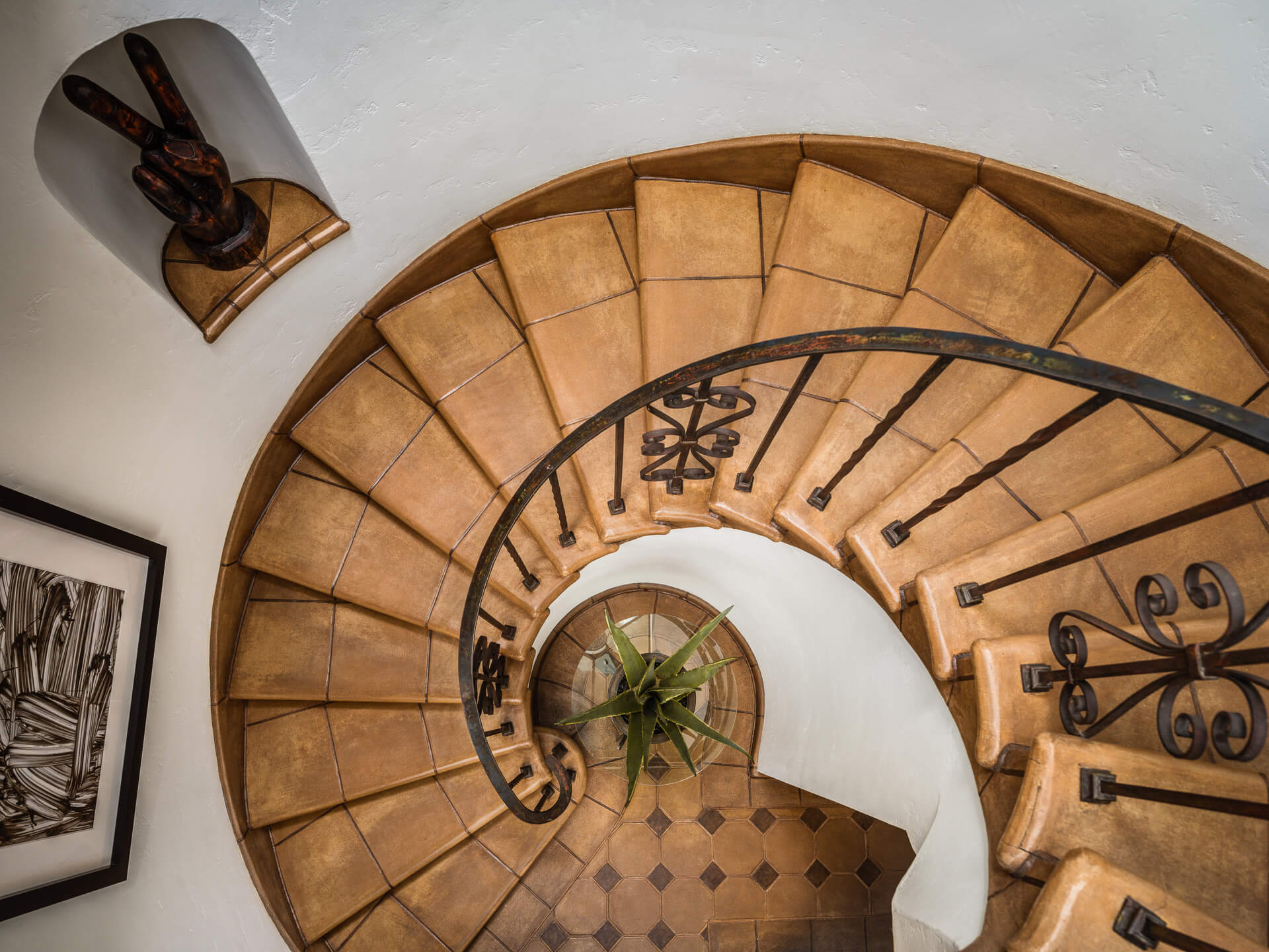 Overhead view of a curved terracotta staircase with decorative wrought-iron railing