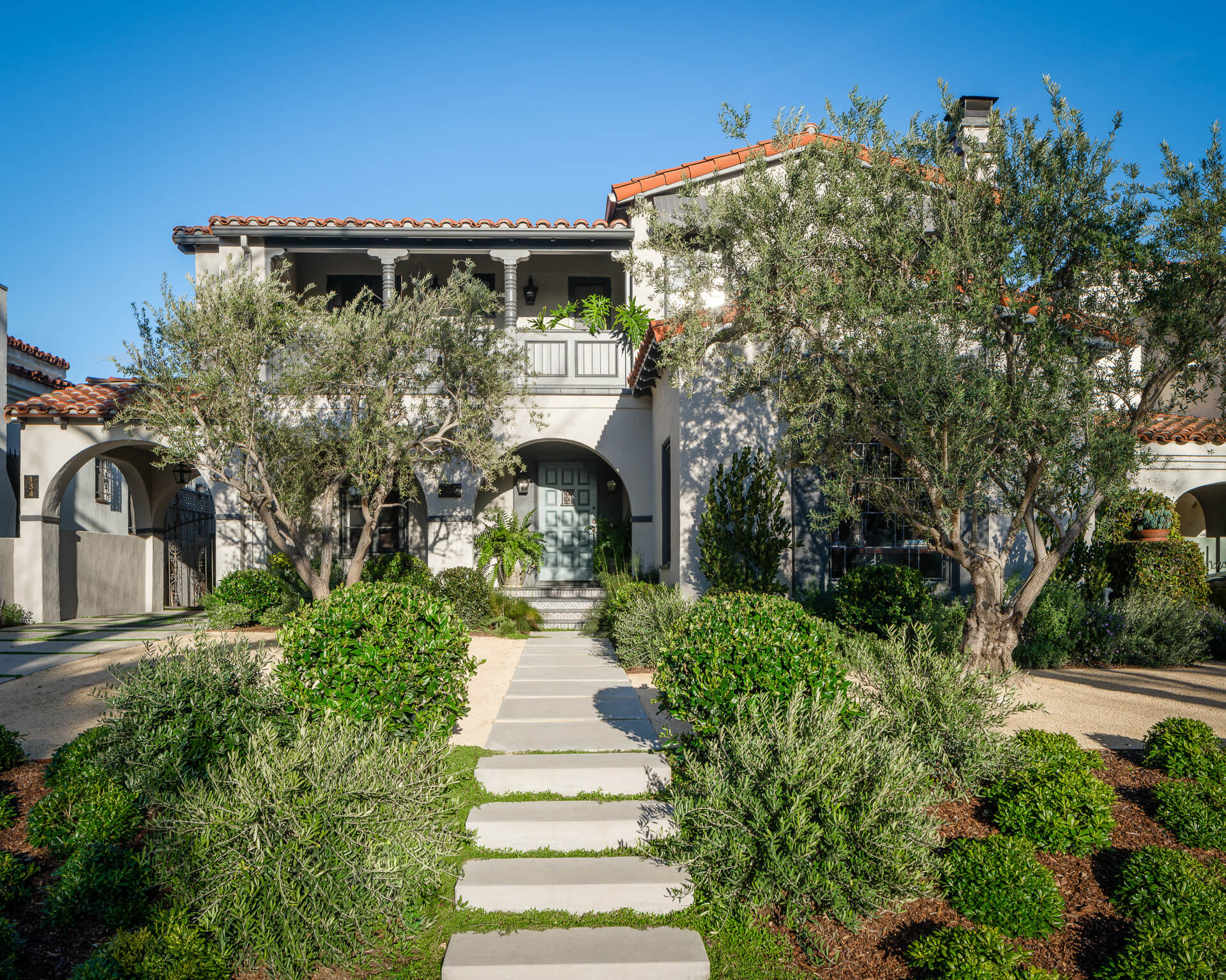 Spanish-style Los Angeles home with arched entry, olive trees and landscaped front garden