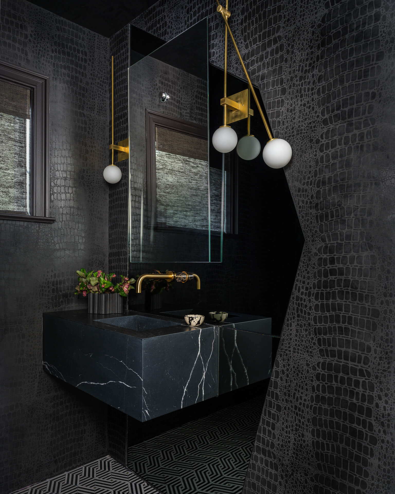 Dark powder room with black textured walls, floating black stone vanity, gold fixtures, and globe pendant lights.