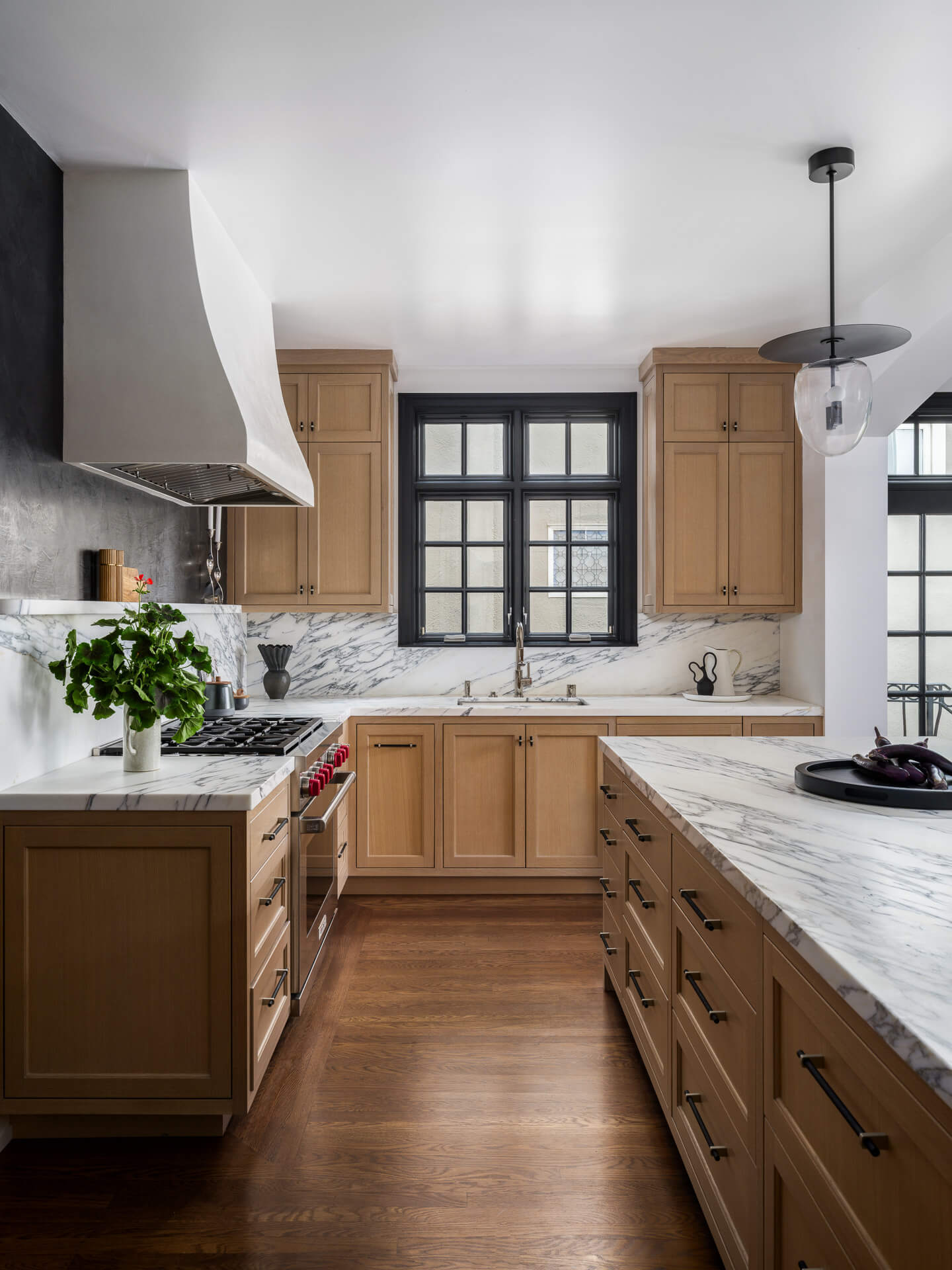 Kitchen with natural wood cabinetry, marble countertops and backsplash, and dark wood floors.