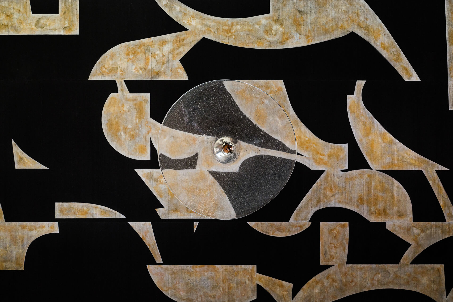 Close-up of abstract black-and-gold wall artwork with layered geometric forms.