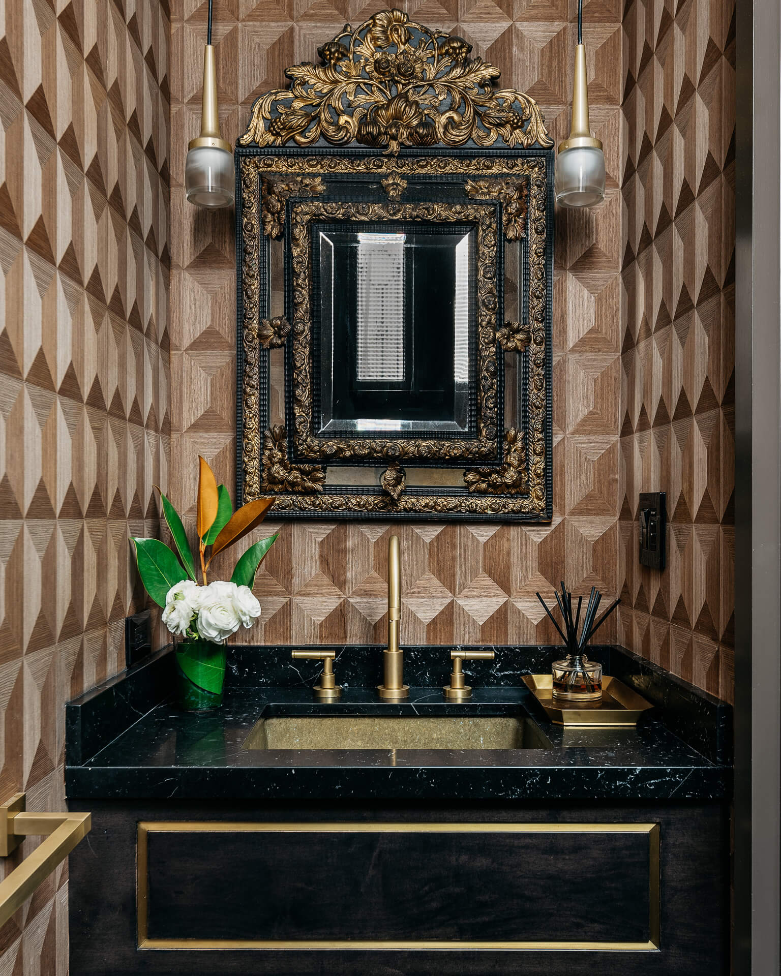 Powder room with geometric wallpaper, ornate dark mirror, black vanity, and brass fixtures.