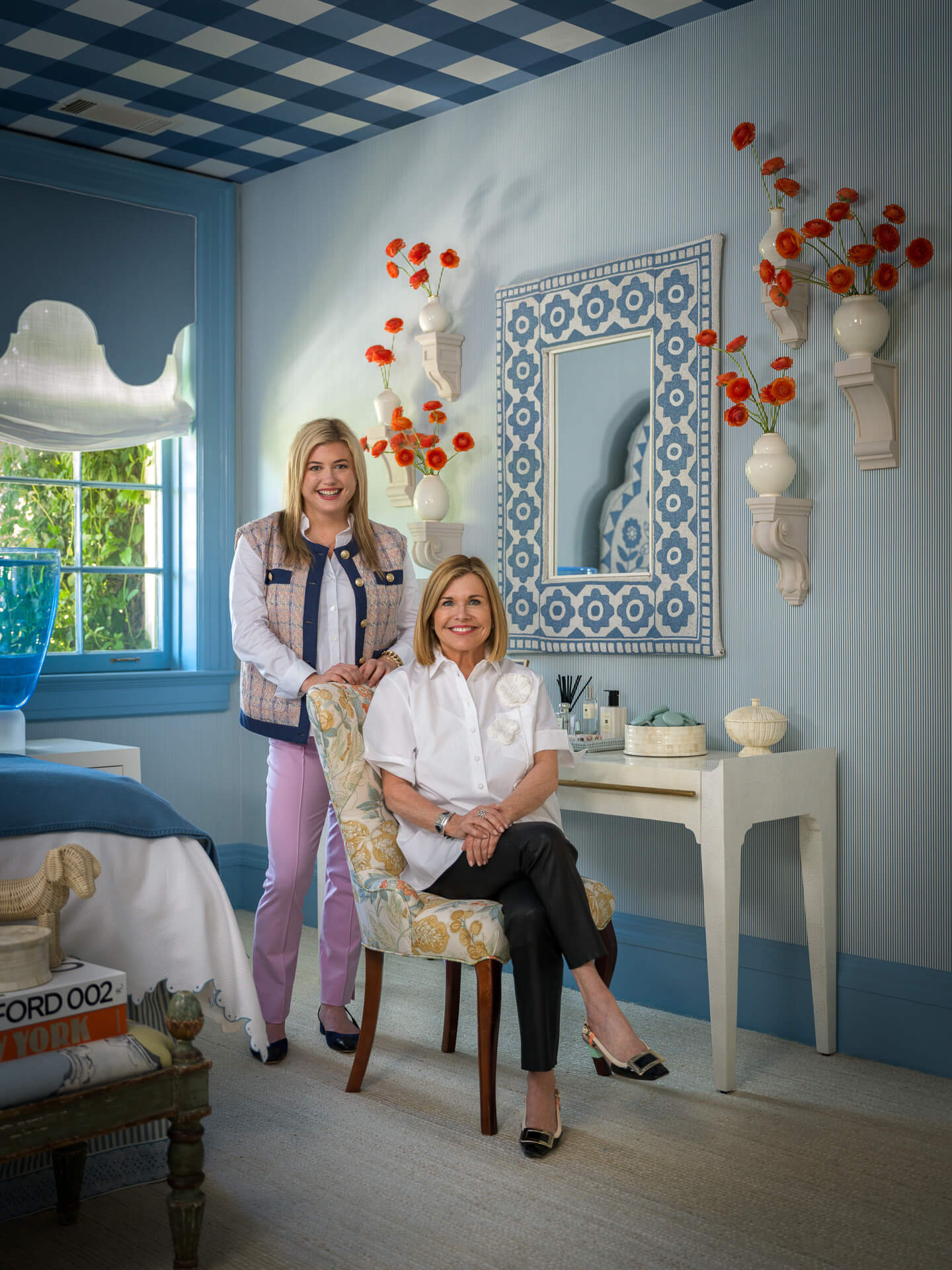 Amy and Samantha Weaver together in a blue interior with colorful artwork and floral accents.