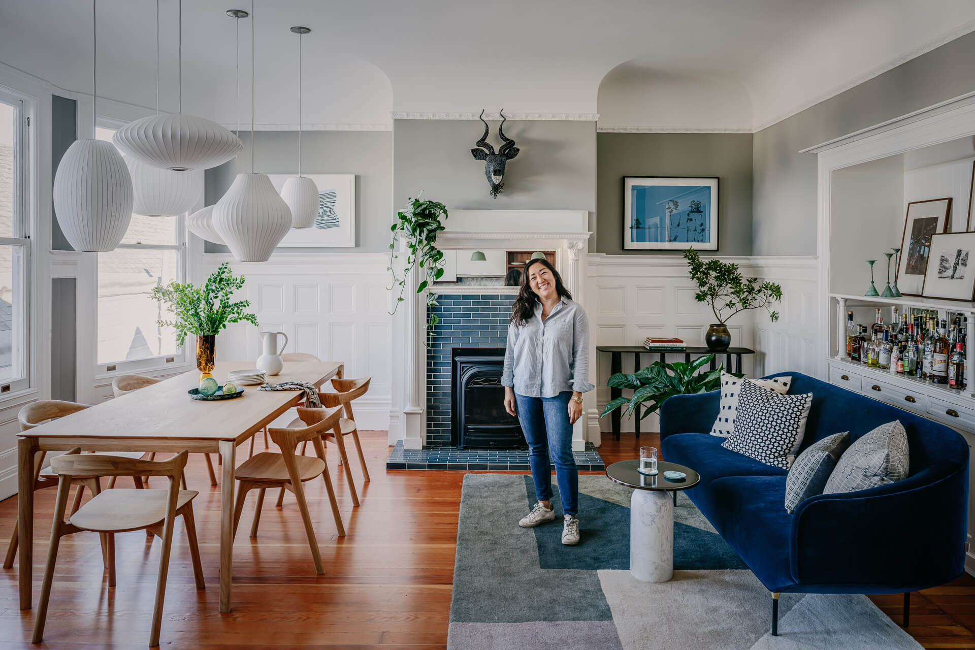 Clara Jung standing in a bright open-plan living and dining room. Image featured Architectural Digest.