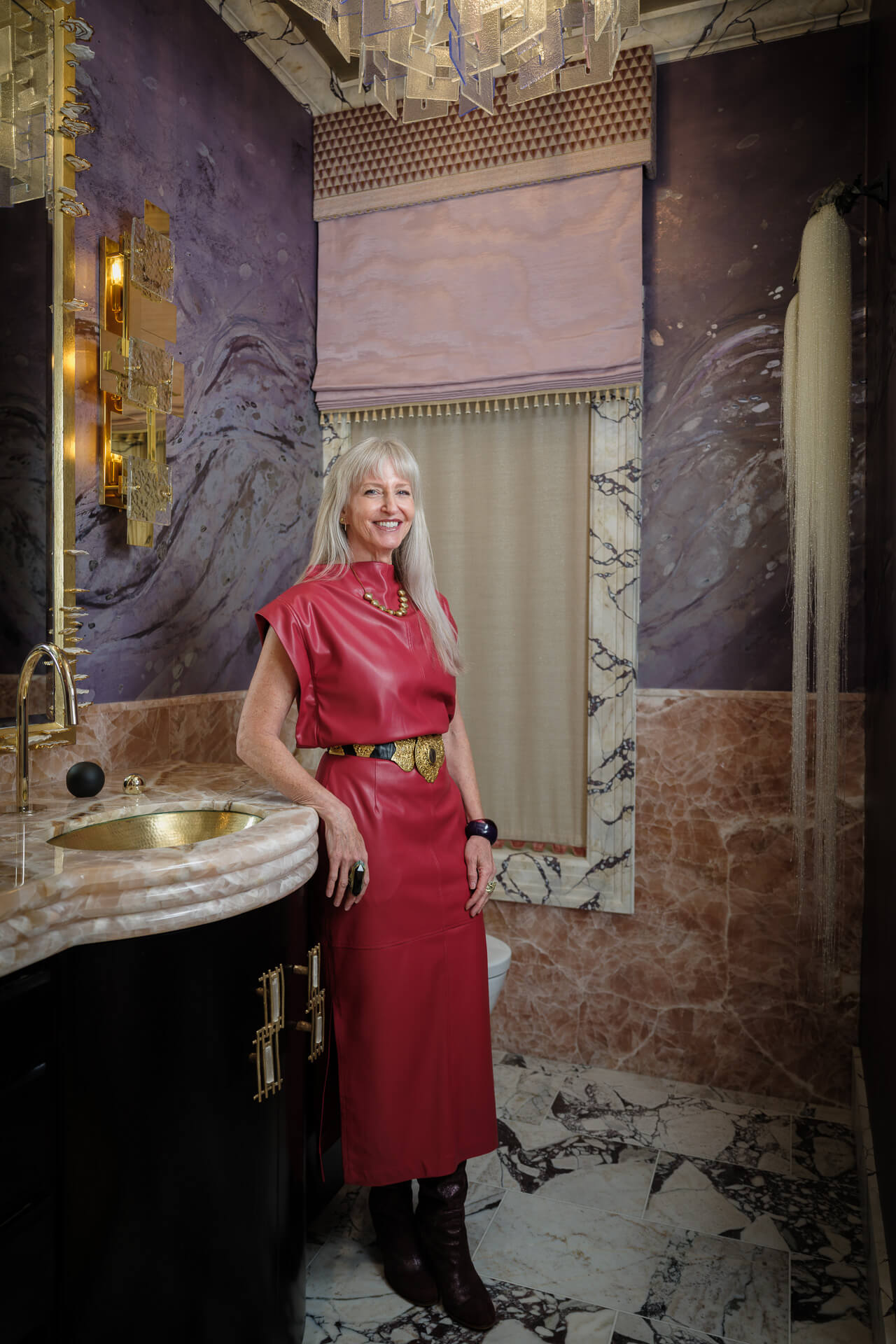 Holly Kopman standing in an ornate interior with richly patterned walls and marble details.