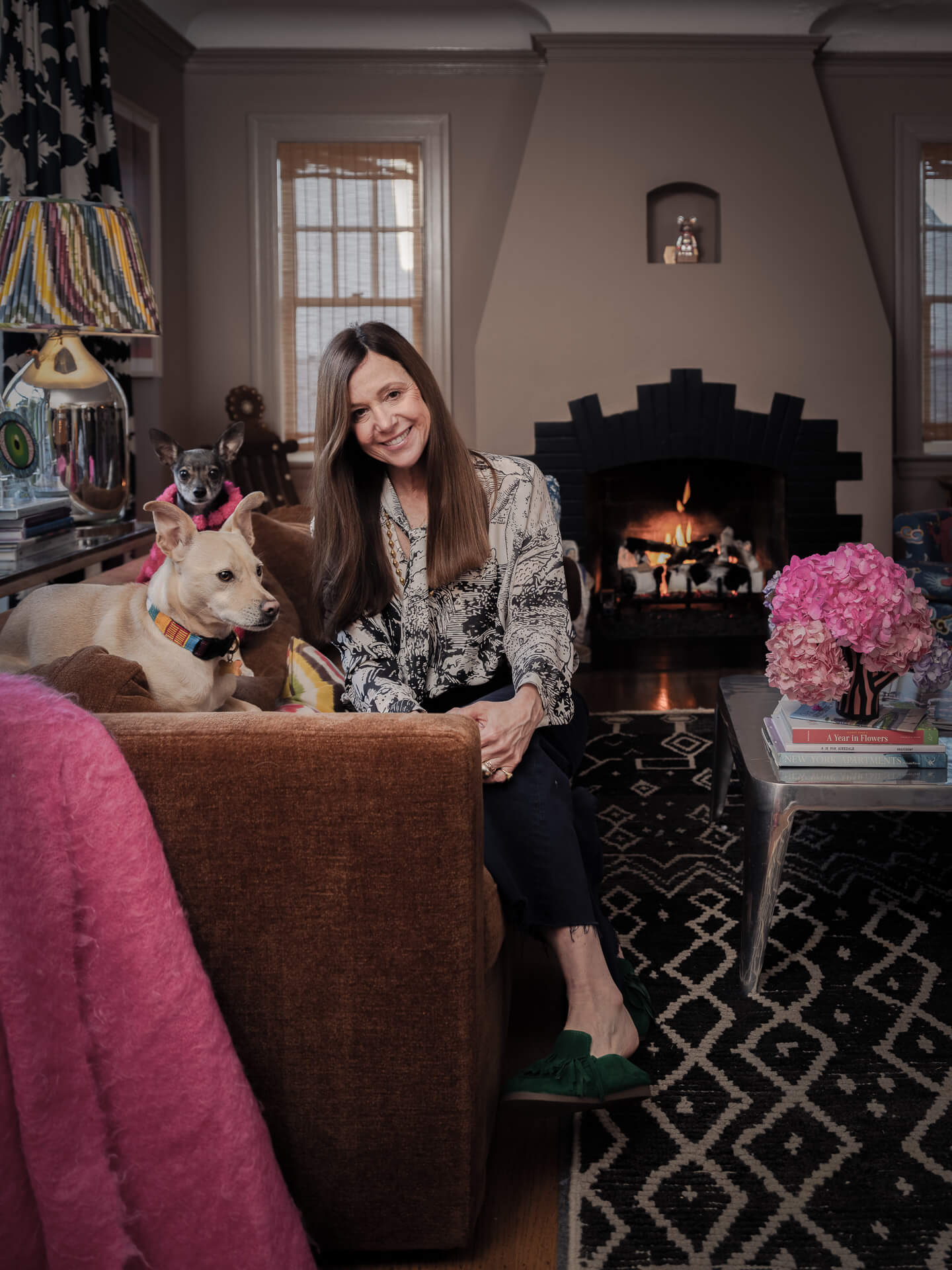 Nicole Balin standing beside a white dog in a colorful sitting room with a fireplace.