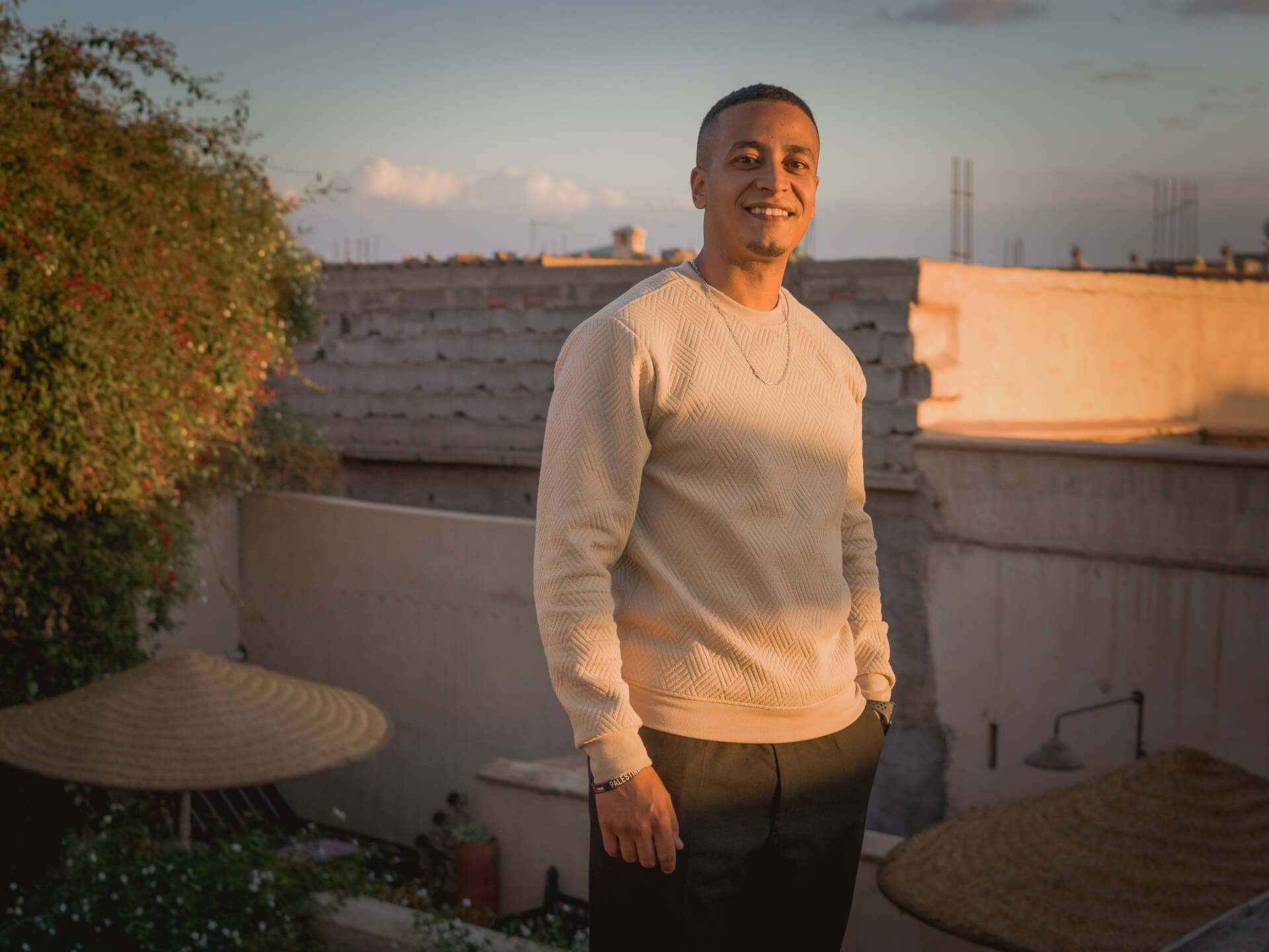 Riad Aaiun staff member standing on a rooftop terrace in warm evening light.