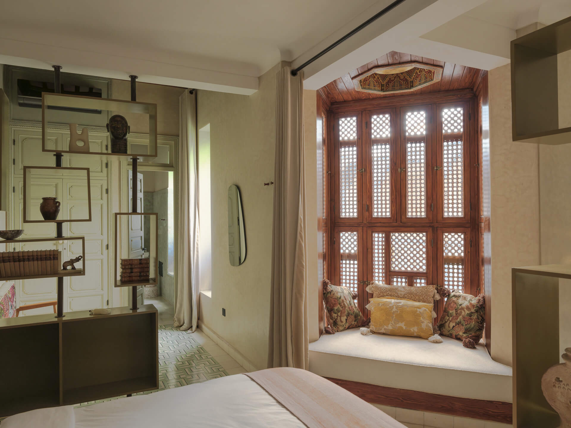 Bedroom with built-in shelving and an ornate carved wood window seat with cushions.