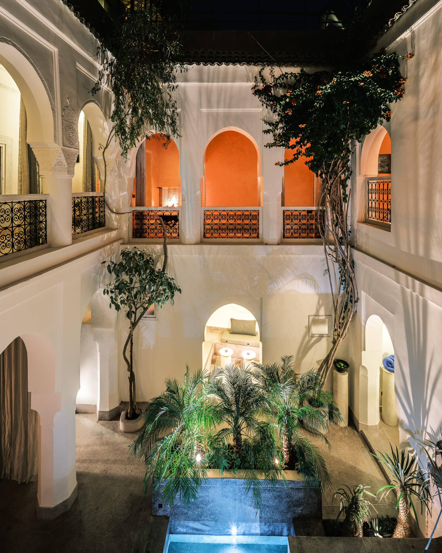 Lush central courtyard surrounded by white arches, balconies, and warm red alcoves